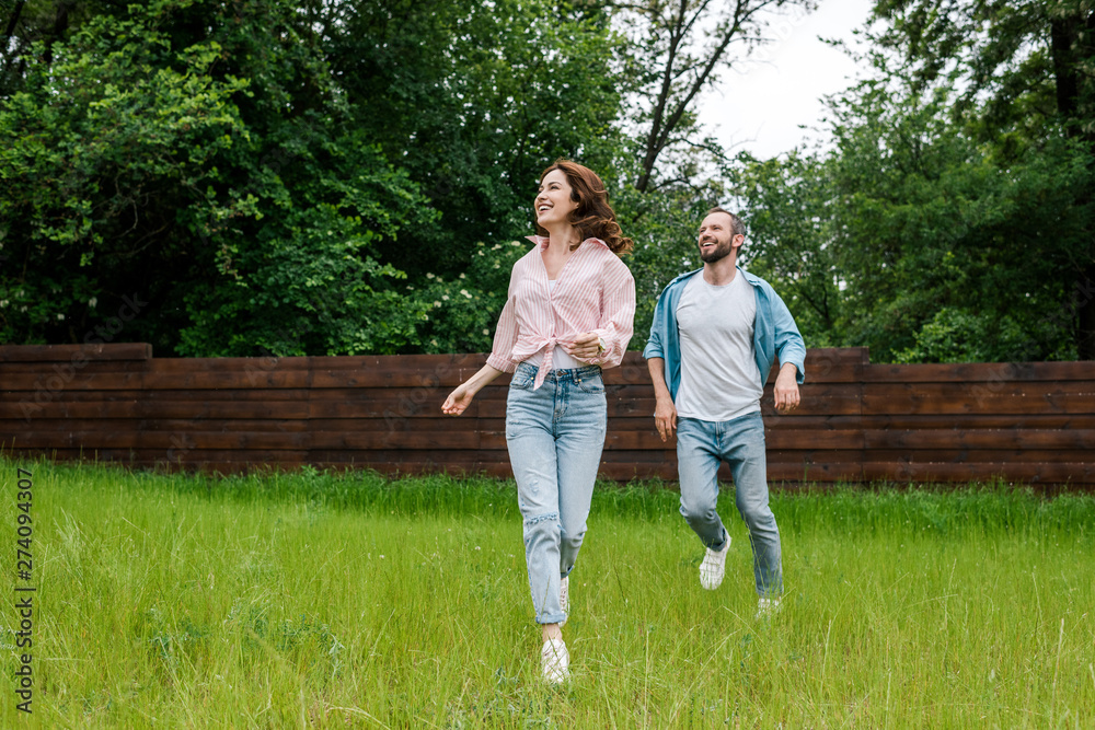 happy man and woman running on green grass outside