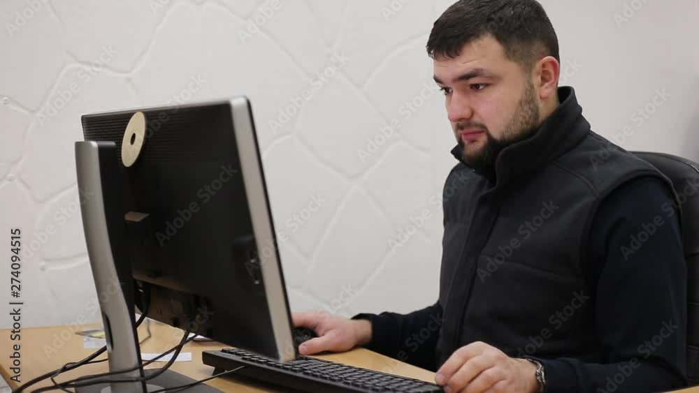 Young bearded office worker man working behind desk on computer. Young bearded office worker man working behind desk on computer.