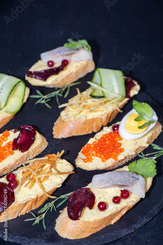 Sandwiches smeared with pharmacomy, on them red caviar, potato Pie, egg, cucumber, beetroot chips. 