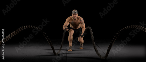 Muscular man working out with battle ropes © Andrey Burmakin