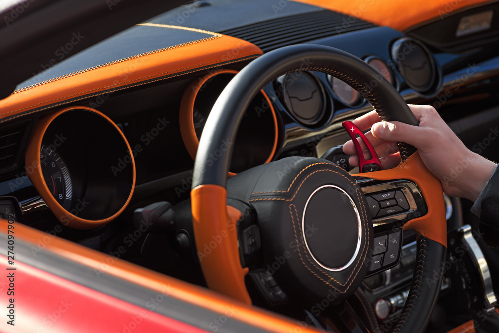 Hands of a man on a steering wheel in a sports car