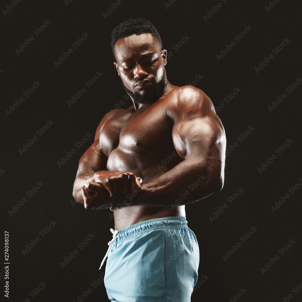 Fototapeta premium African bodybuilder showing biceps in black studio