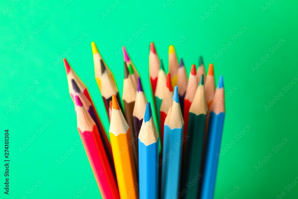 Fototapeta Multicolored pencils against green background, closeup