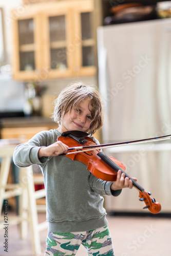 5 year old boy playing a violin at home photo