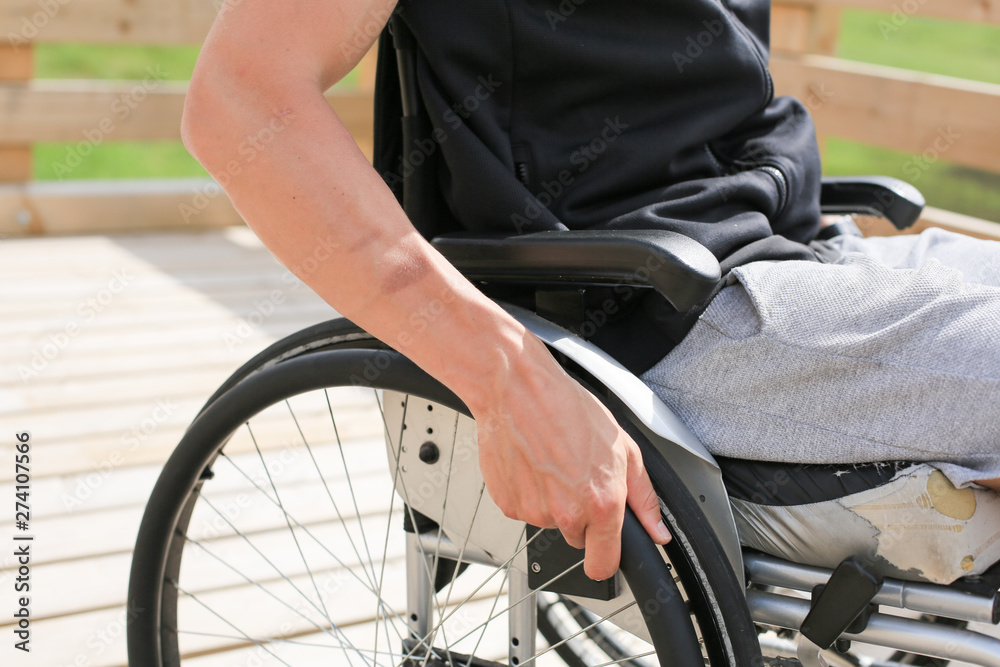 Obraz premium Disabled young athletic man on a wheelchair holding and turning wheels with hand engage in sports