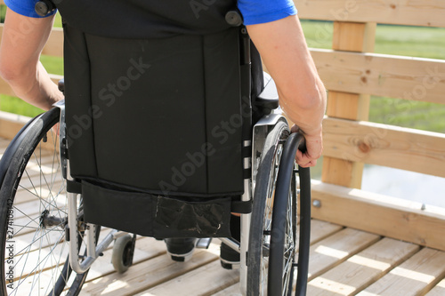 Disabled young man on a wheelchair holding and turning wheels with hand