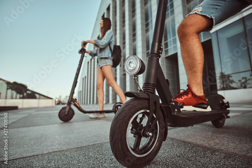 Young couple are making interesting composition from their scooters while posing for photographer.