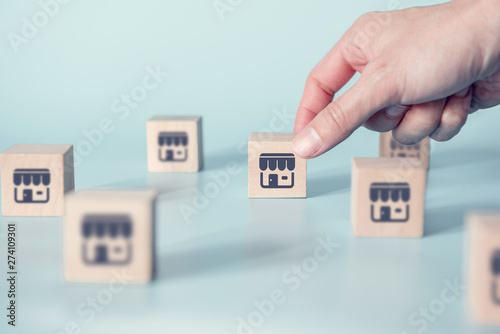 Woman hand choose wood blog with franchise icon on blue background. Franchise business concept.