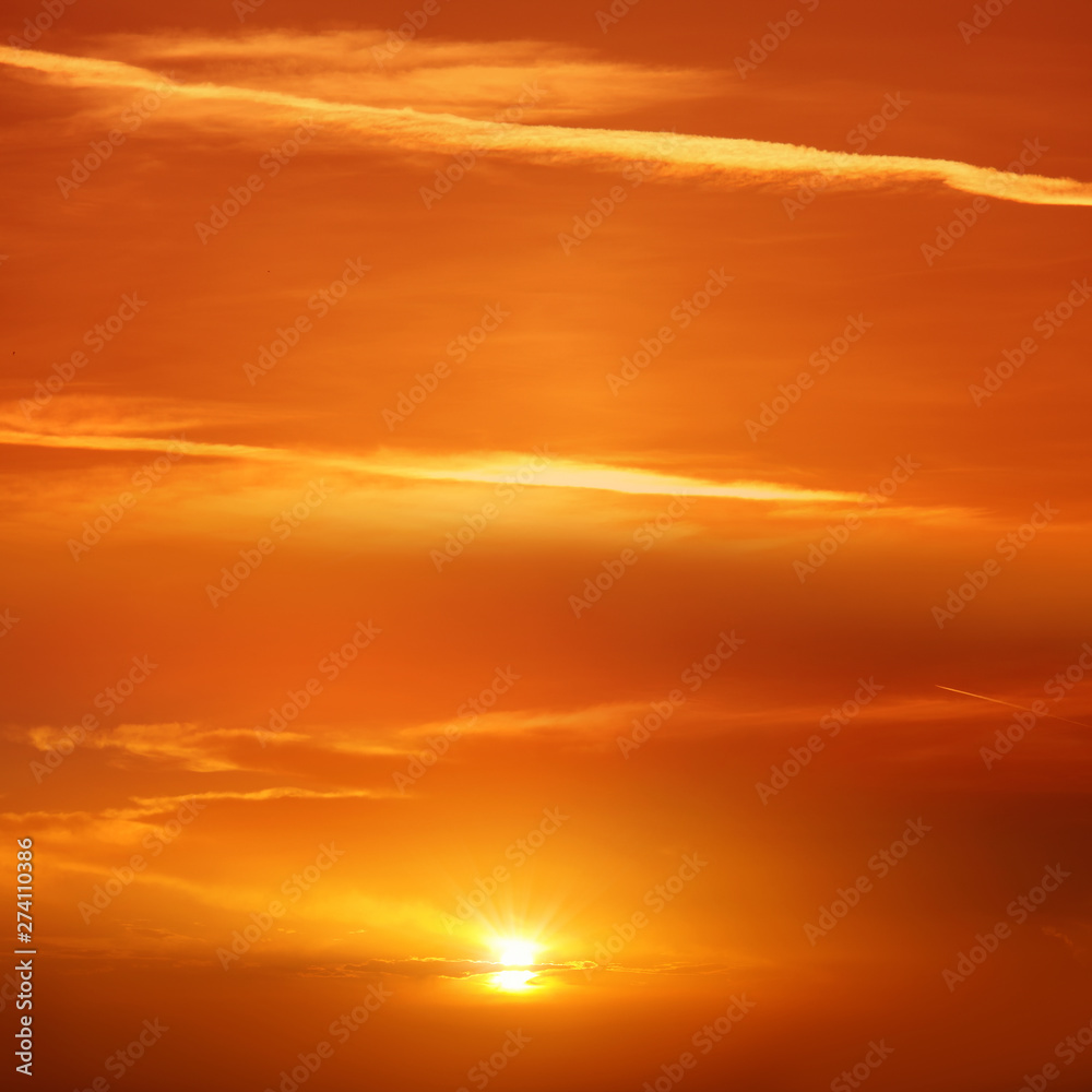 Beautiful cloudscape of orange colored sunset sky with shining sun