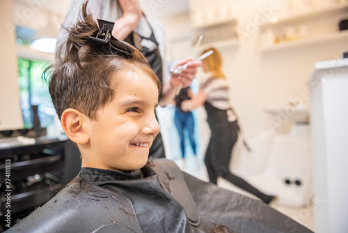Child little boy in the barber shop hair cut professional smiling portrait looking at mirror - Little boy in the barber shop hair cut professional toddler child getting his first haircut profile