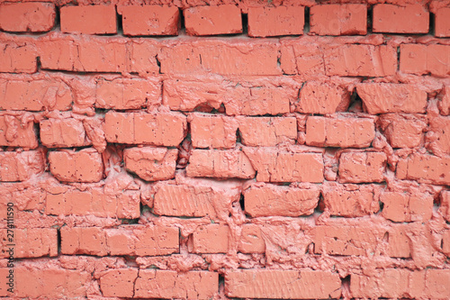 Background and texture painted red brick wall of broken and uneven bricks with uneven cement seam...