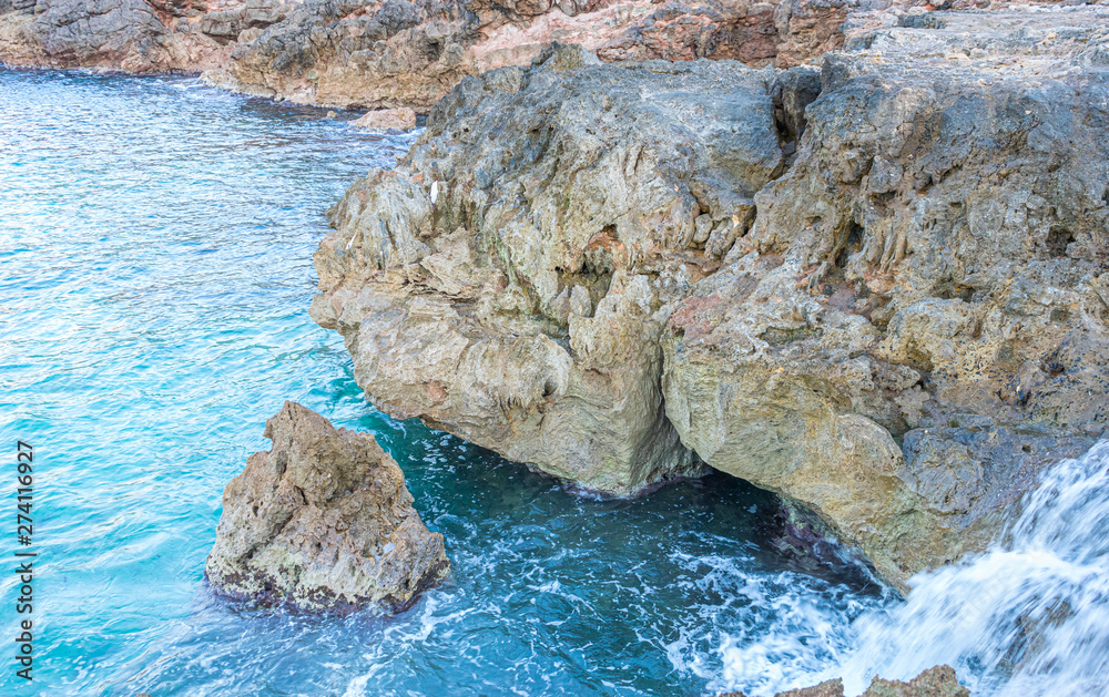 Travel, Summer cliff next to the Mediterranean Sea, strong waves break with the rocks and leave blue and turquoise colors along with the foam of the sea.
