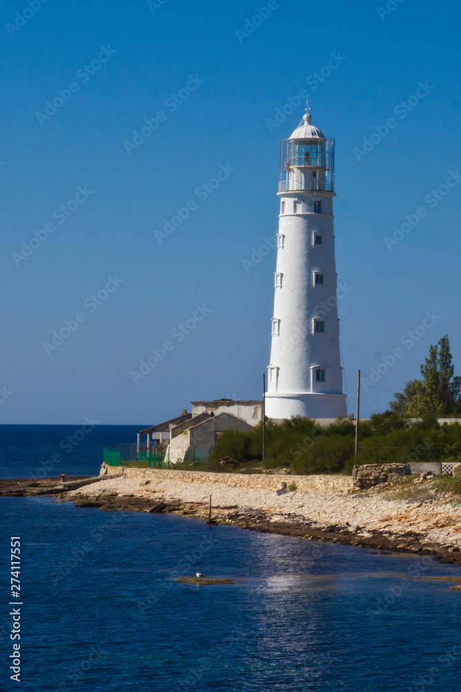 white lighthouse by the sea on a sunny summer day