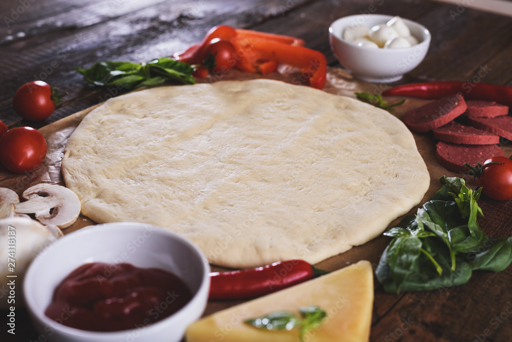 Raw rolled pizza dough with ingredients on edges Raw rolled pizza dough with ingredients on edges