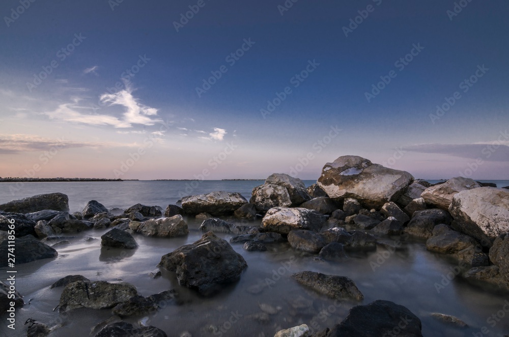 Beautiful coastal seascape with rocks in the foreground at sunset