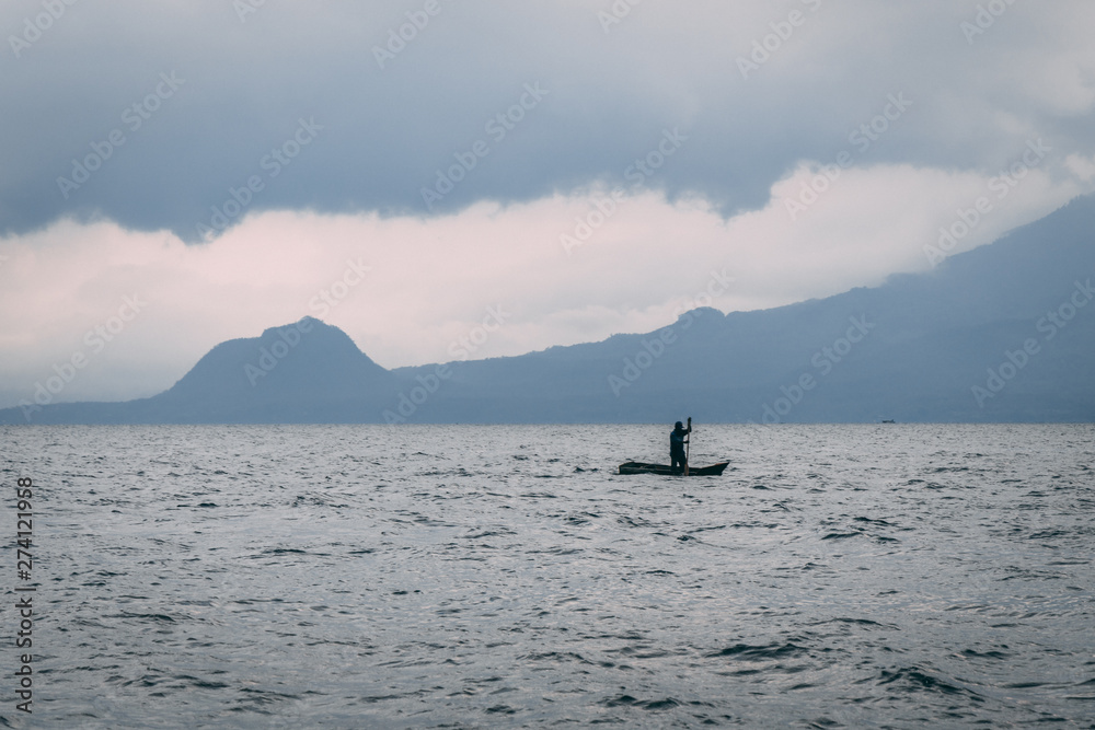 Obraz premium man on kayak on lake in front of mountain