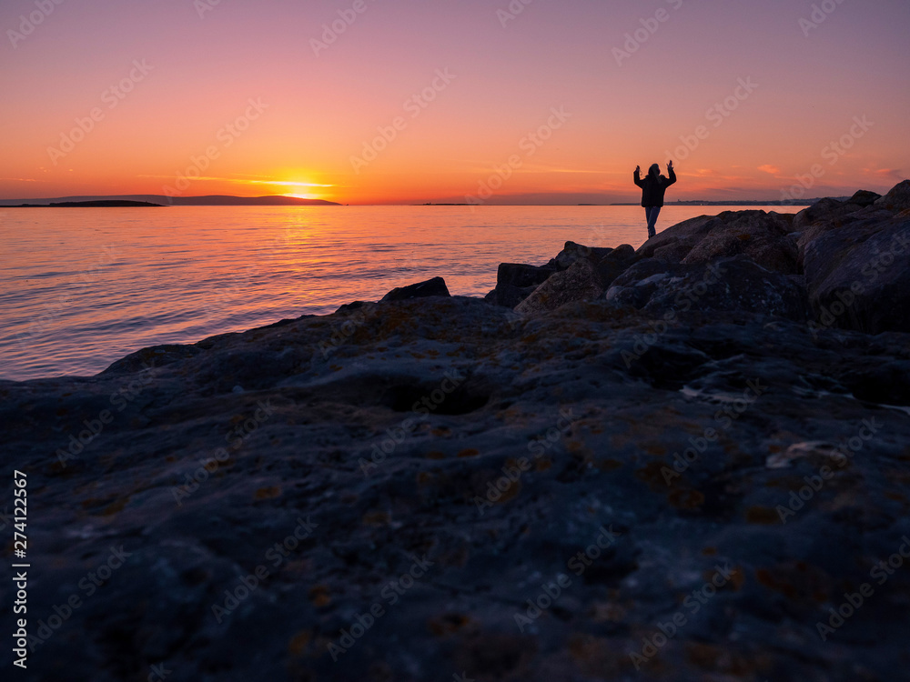 Silhouette of a teenager, hands in the air, sunset over ocean, concept: emotion, excitement. Silhouette of a teenager, hands in the air, sunset over ocean, concept: emotion, excitement.