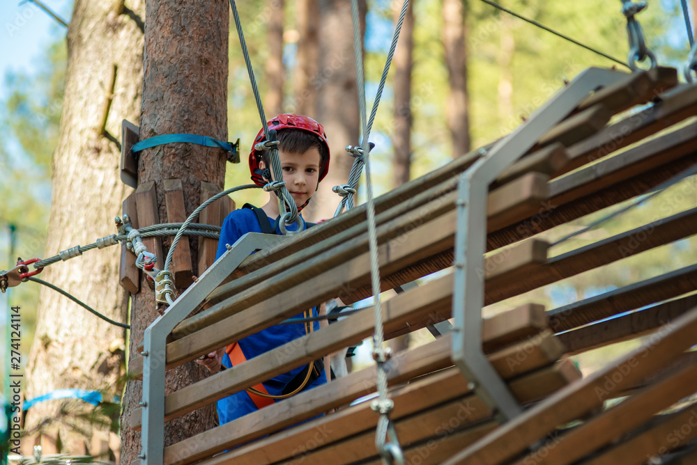European sporty boy is doing activity in adventure rope park with all climbing equipment. European sporty boy is doing activity in adventure rope park with all climbing equipment.