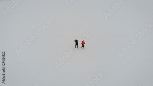 aerial view of two male hikers walking in untouched snow landscape. aventures journey trip scenery of people together