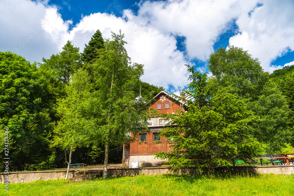 Obraz premium Vasil Levski mountain hut in Old mountain (Stara planina), Old river national park, Bulgaria. Summer landscape, green forest with blue sky and puffy white clouds