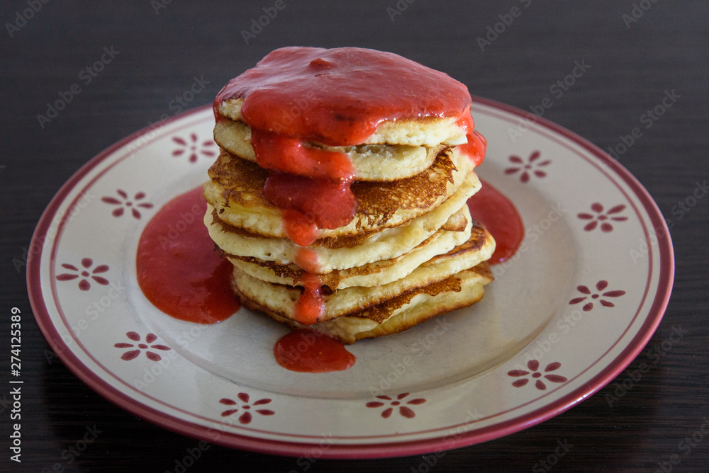Stack of Homemade pancakes with freshly blended strawberries on plate.