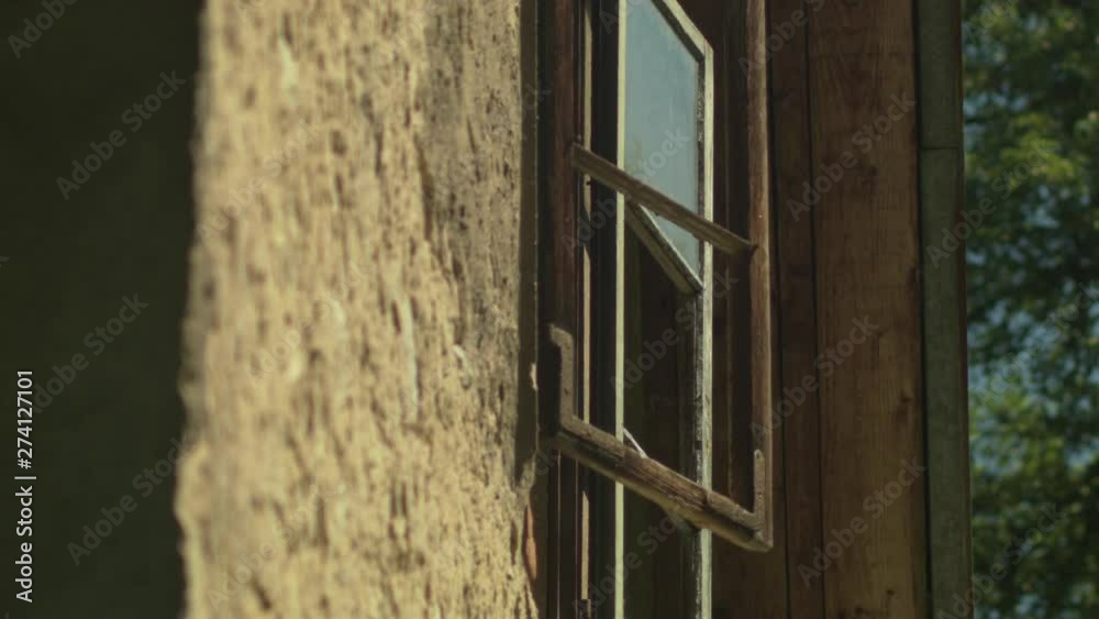 Bees hover and fly in the foreground outside an open window of an old rustic home in the countryside. Close-up. Bees hover and fly in the foreground outside an open window of an old rustic home in the countryside. Close-up.
