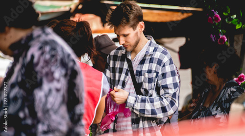 young male walking in a crowd in a city street during daytime in a sunny season