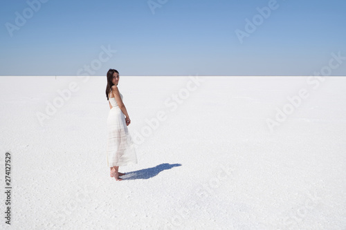 Dark-haired girl in a white dress, salt lake Elton in the Volgograd region in Russia.
