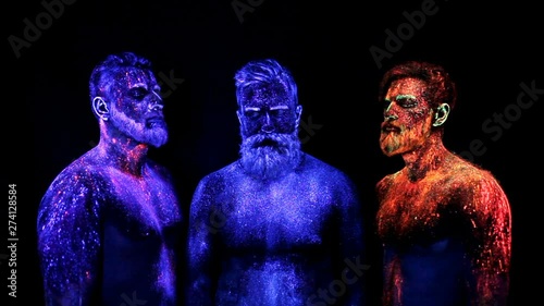 Three bearded men in UV powder are standing static photo