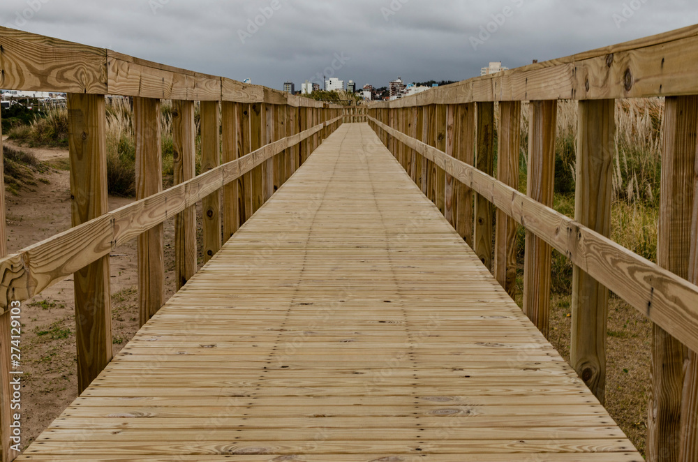 wooden footbridge over the beach in cloudy winter day