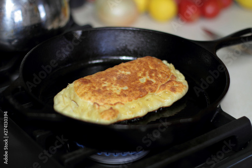 Pan fried calzone cooking in a cast iron skillet on a stove.
