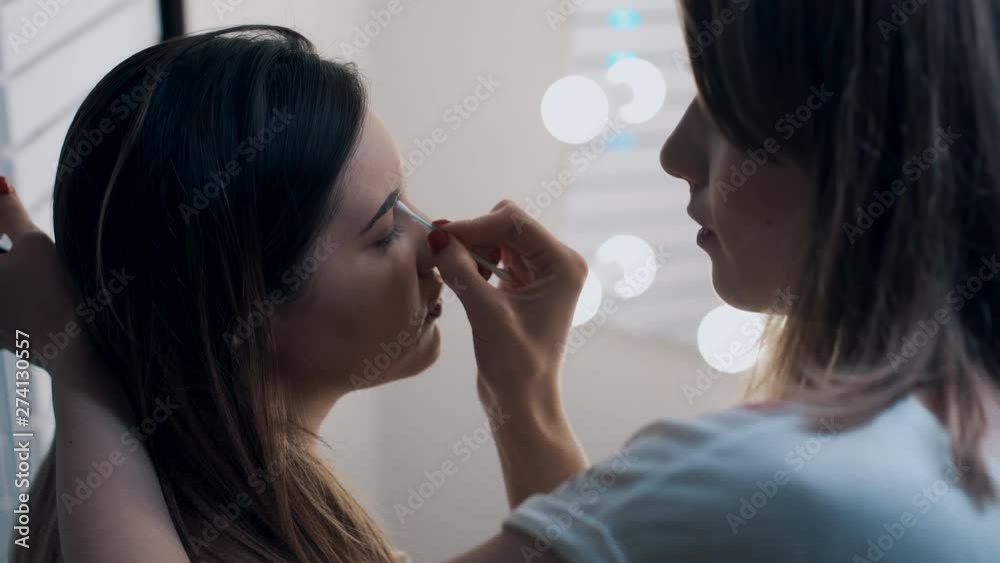 make up artist tweezing eyebrows of young beautiful female make up artist tweezing eyebrows of young beautiful female