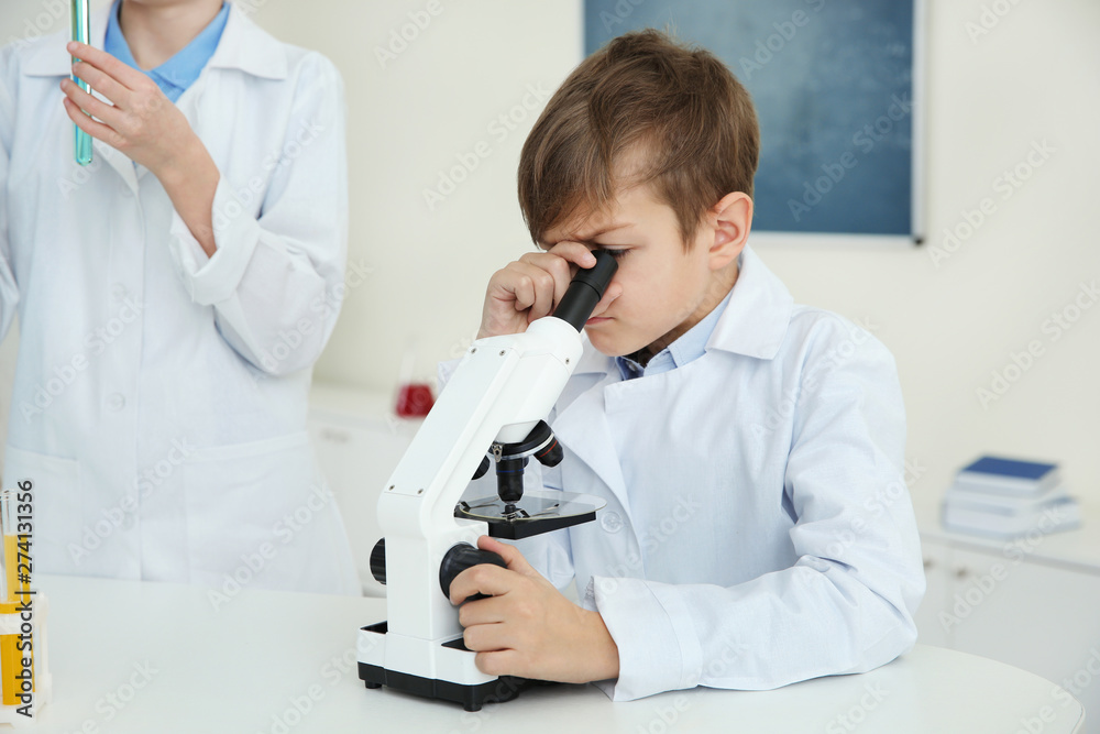Pupil looking through microscope at table in chemistry class Pupil looking through microscope at table in chemistry class