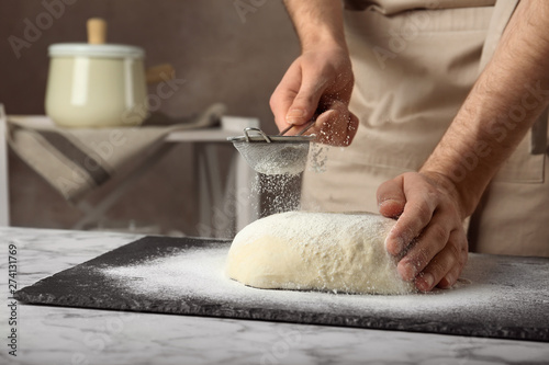 Male baker preparing bread dough at table, closeup