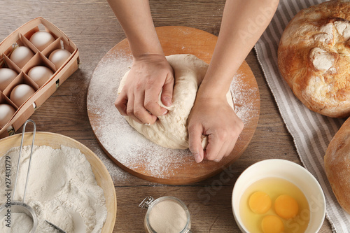 Female baker preparing bread dough at kitchen table, above view