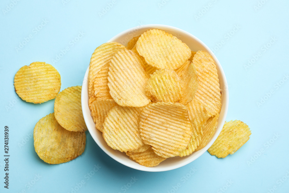 Delicious crispy potato chips in bowl on color background, top view Delicious crispy potato chips in bowl on color background, top view