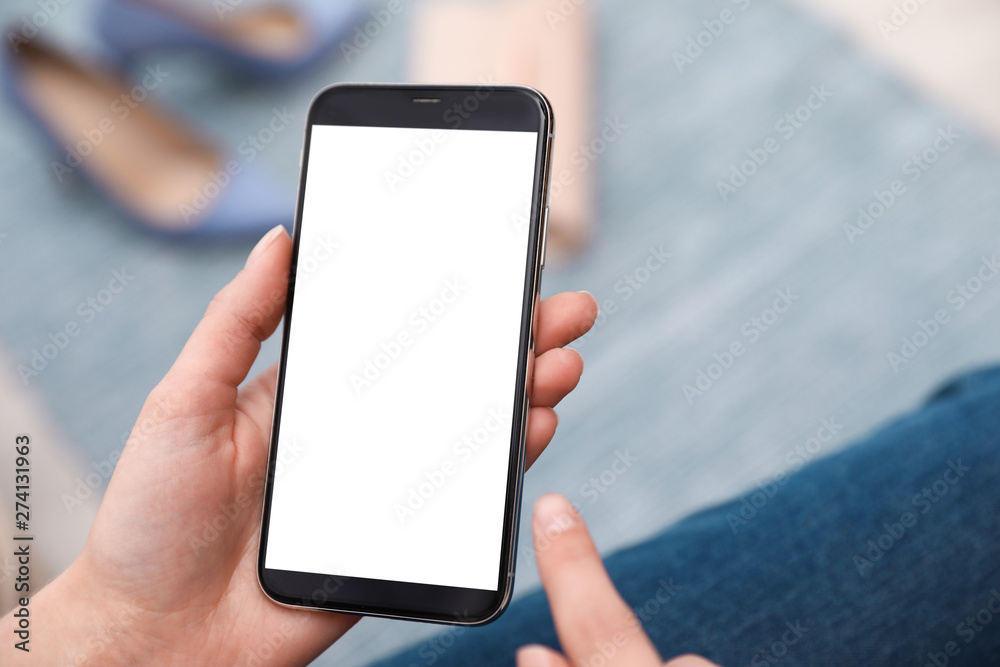 Woman holding smartphone with blank screen indoors, closeup of hands. Space for text