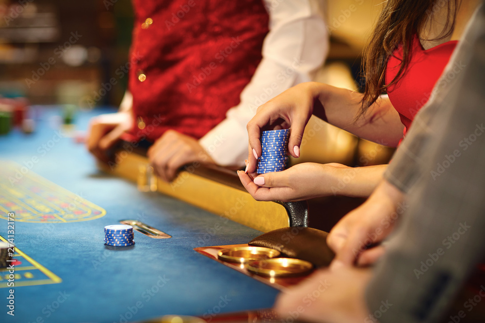 Hands with chips at poker roulette table gambling in a casino.