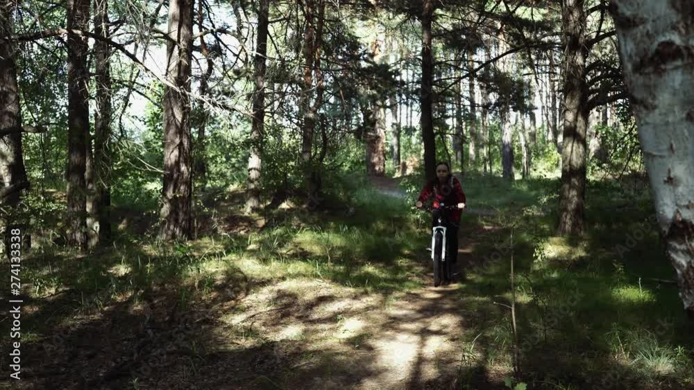 Active sporty woman riding mountain bike on forest trail. Woman riding a bike in the woods Active sporty woman riding mountain bike on forest trail. Woman riding a bike in the woods