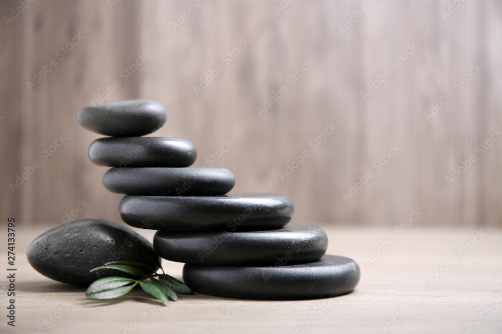 Black spa stones with branch on wooden background. Space for text Black spa stones with branch on wooden background. Space for text