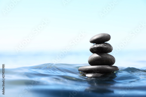 Stack of stones in sea water, space for text. Zen concept