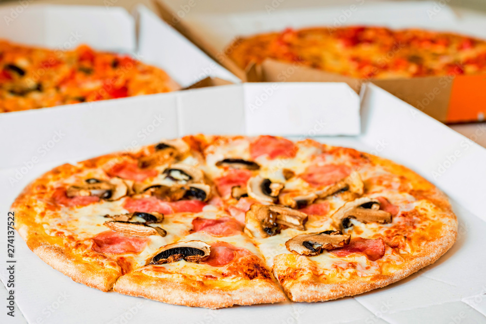 Delicious pizza with tomatoes, mushrooms and cheese in paper box
