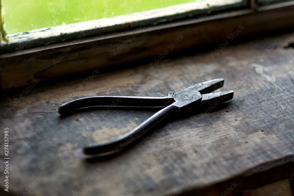 Old rusty plier on wooden shelf near window. Tool for carpentry work. Old rusty plier on wooden shelf near window. Tool for carpentry work.