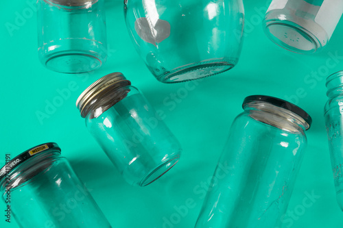 Glass jars with lids, teal green background, top view flat lay recycling concept