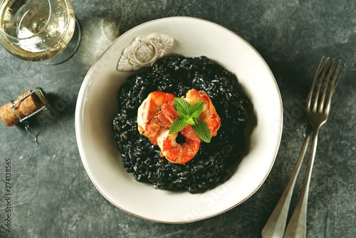 Delicious Italian risotto with grilled big tails of shrimp and cuttlefish ink (squid-ink). Black risotto. Healthy tasty food.  Top view. Copy space. 