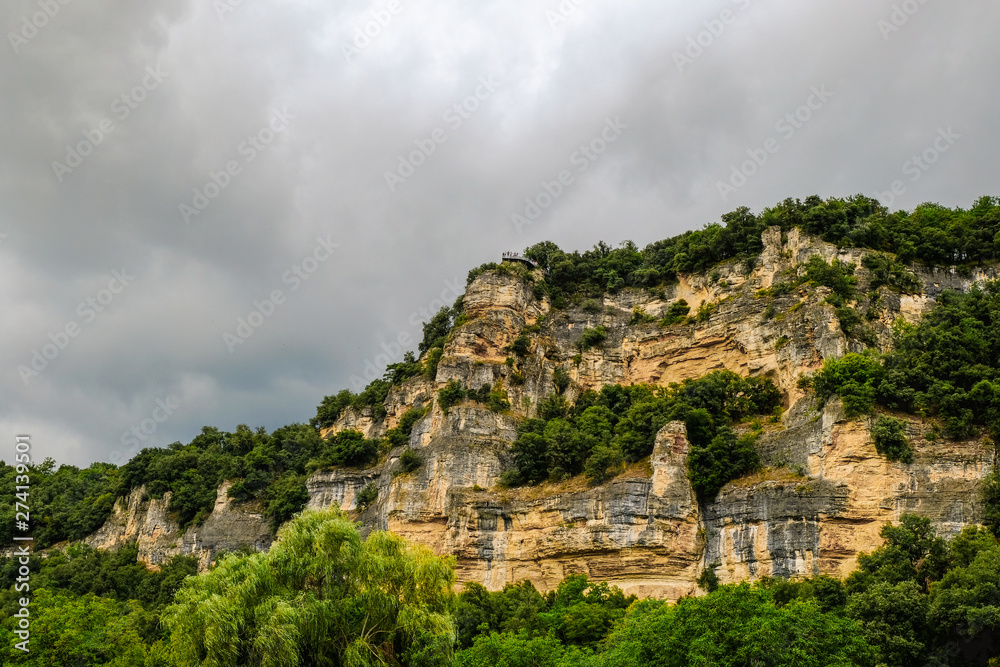 Dramatic grey sky and cliffs above the valley of the Dordogne River. Village of La Roque Gageac, France.