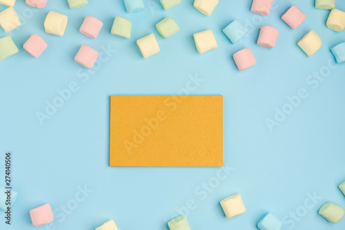 Blue paper background with marshmallow and notepad. Place for your text. Cozy sweet background