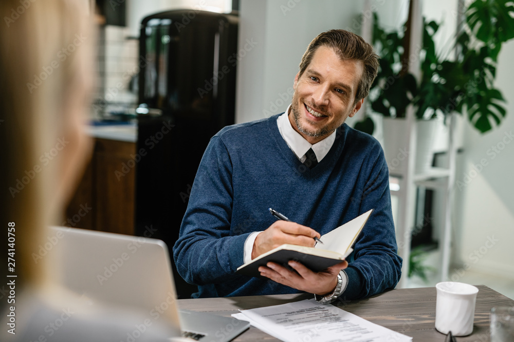 Happy financial advisor planning home budget with his client. Happy financial advisor planning home budget with his client.