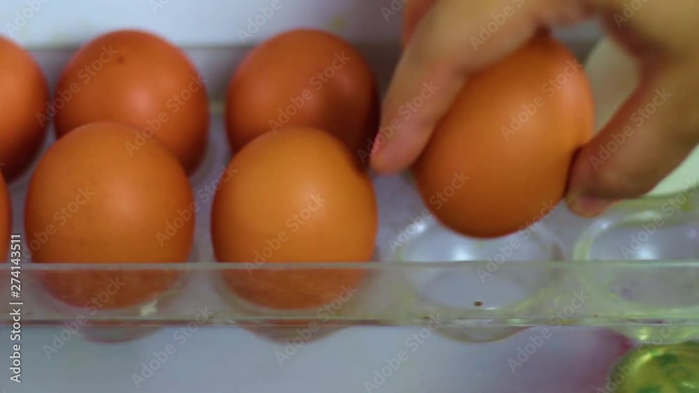 Hand taking fresh Eggs in a refrigerator tray hole in the refrigerator. Hand taking fresh Eggs in a refrigerator tray hole in the refrigerator.