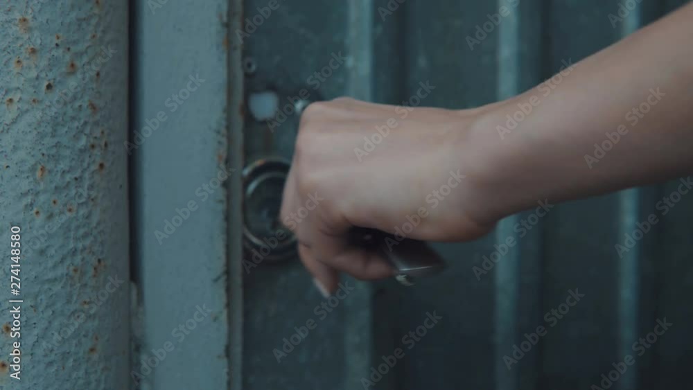 The girl opens the door lock with a large key and walks in the door The girl opens the door lock with a large key and walks in the door